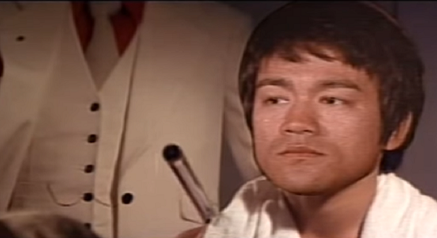 Uma cena de um filme em que um sósia de Bruce Lee está sentado diante de um espelho.
